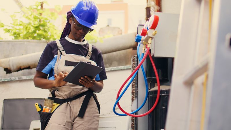 Knowledgeable professional calibrating ac gauges vacuum pump during comissioned condenser maintenance. Capable specialist looking for potential low pressure in air conditioner cooling system